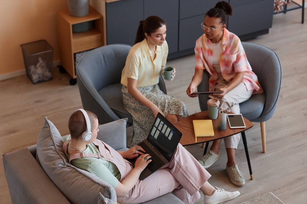 High angle portrait of young women using devices in meeting and working on IT project together